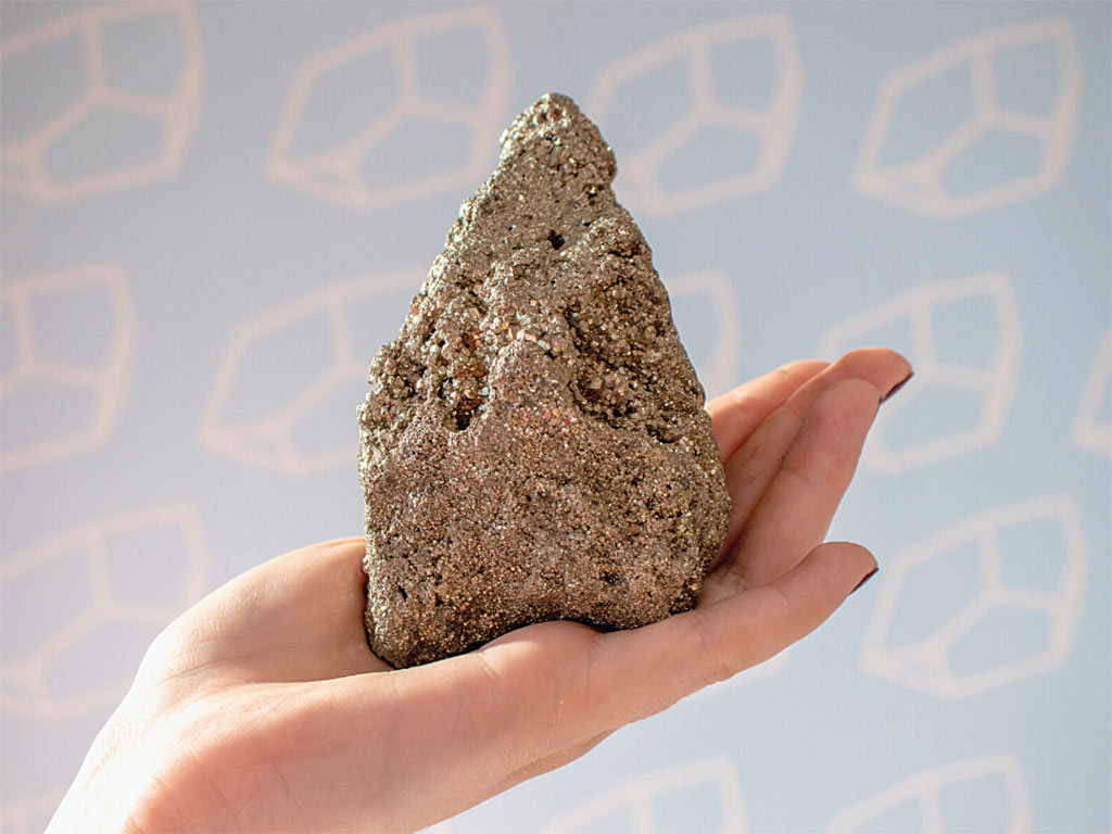 foto de pedra pirita em cima de uma mao feminina
